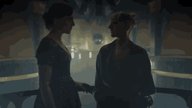 two women standing next to each other in a dark room holding hands