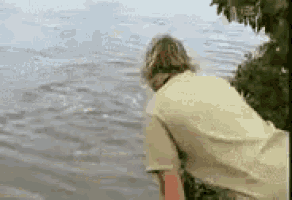 a man in a yellow shirt is standing in the water .