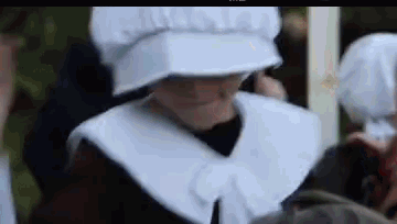 a close up of a person wearing a white hat and a white collar .