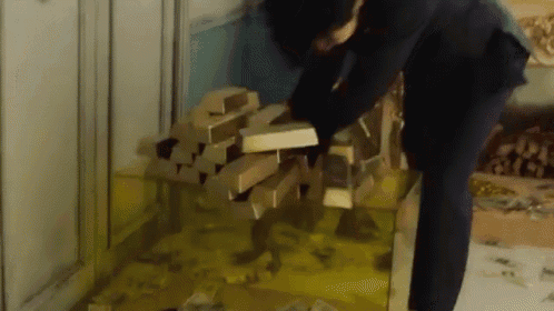 a man in a suit is reaching for a pile of gold bars .