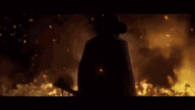 a man in a cowboy hat stands in front of a fire with the words eastern road above him