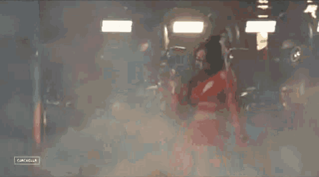 a woman in a red crop top and pants is standing in a dark room with smoke coming out of it .