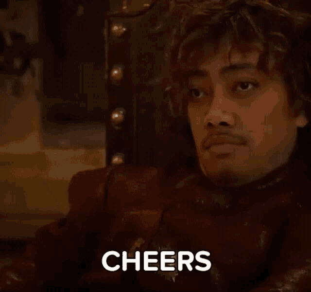a man in a red jacket is sitting in a chair with the word cheers written on his face .