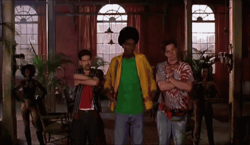 a group of men are dancing in a room with a woman in a tie dye shirt