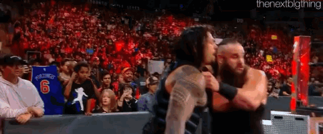 two wrestlers hugging in front of a crowd with a sign that says world heavyweight