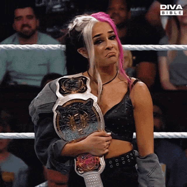 a woman with pink hair is holding a diva bible wrestling championship