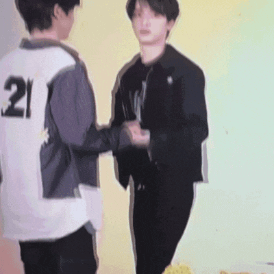two young men are shaking hands and one has the number 21 on his back .
