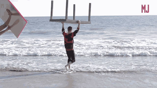 a man carrying a chair over his head on a beach with m.i.