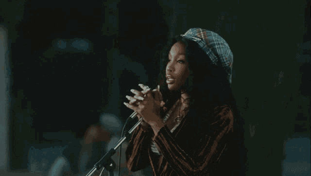 a woman singing into a microphone while another woman applauds behind her