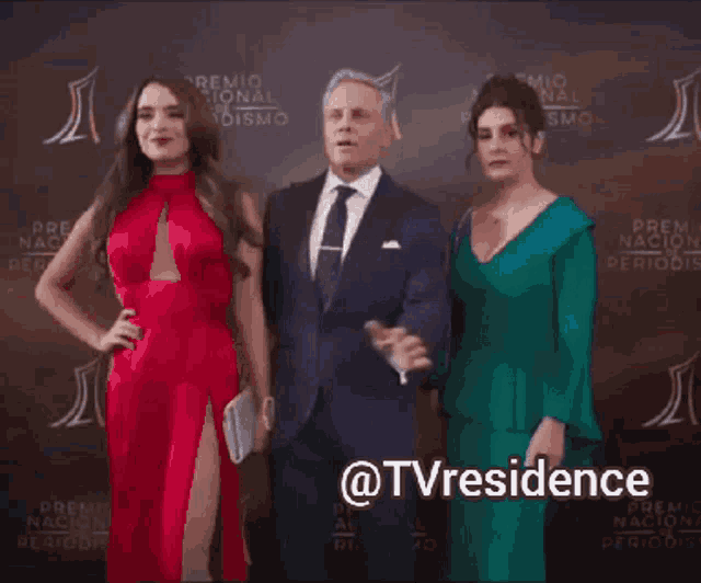a man in a suit and tie stands between two women on a red carpet with the hashtag @tvresidence