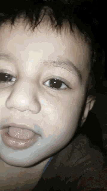 a close up of a young boy 's face with his tongue out