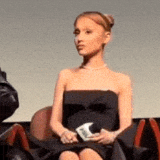 a woman in a black strapless dress sits in a chair
