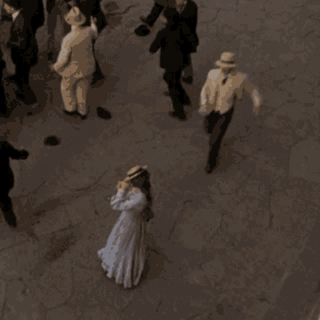 a woman in a white dress stands in the middle of a crowd