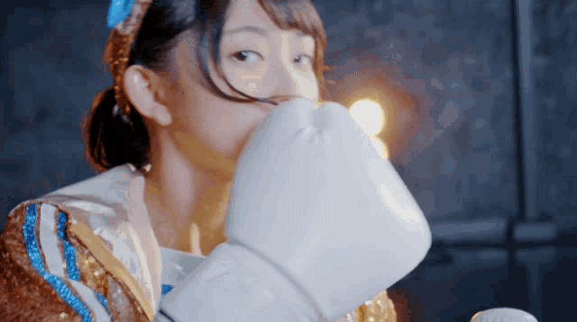 a woman wearing white boxing gloves covering her face