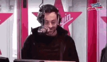 a man wearing headphones is talking into a microphone in a radio station .