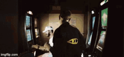 a man is standing next to a woman playing a video game in a dark room .