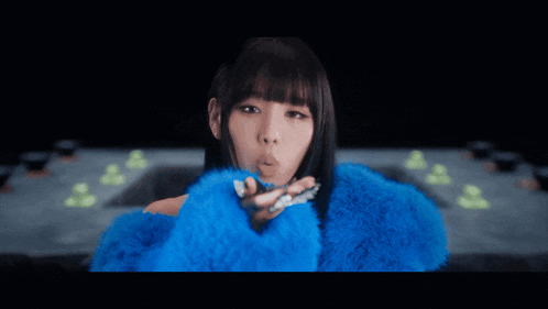 a woman in a blue fur coat is surrounded by confetti falling on her face