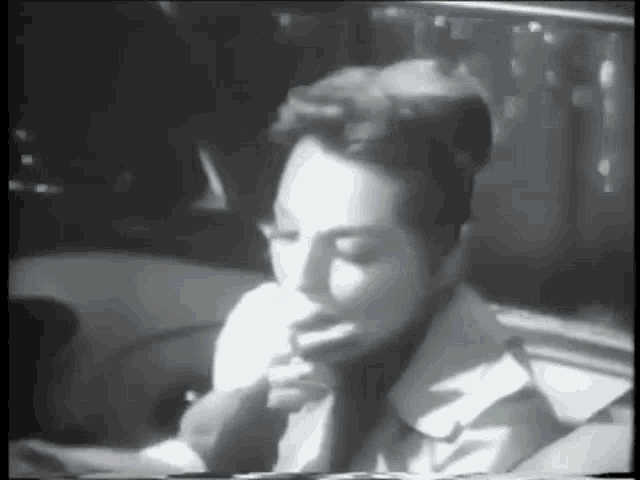 a black and white photo of a woman smoking a cigarette in a car