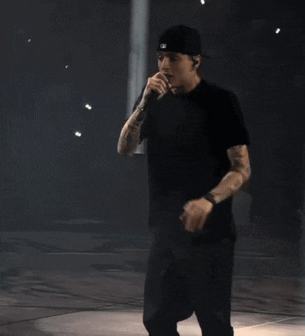 a man singing into a microphone with a tattoo on his arm that says ' eminem '