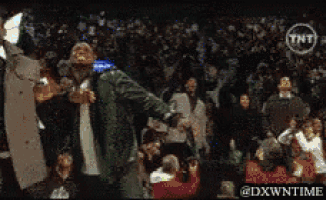 a man in a suit is dancing in front of a crowd with a tnt logo behind him