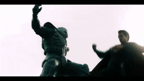 a man in a superhero costume is fighting another man in a cape .
