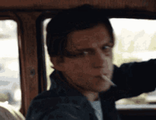 a man is smoking a cigarette in a car and looking out the window .