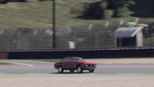 a red car is driving on a track with a green stripe on the side