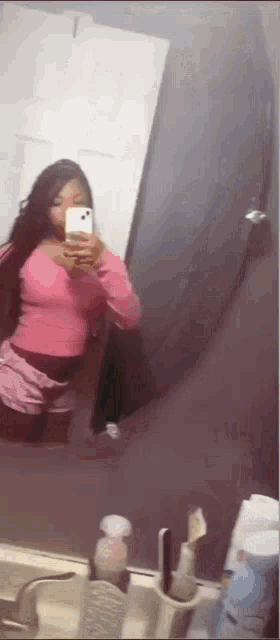 a woman is taking a selfie in front of a mirror .