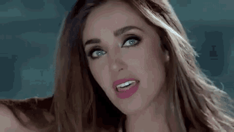 a close up of a woman 's face with long hair and a pink lip .