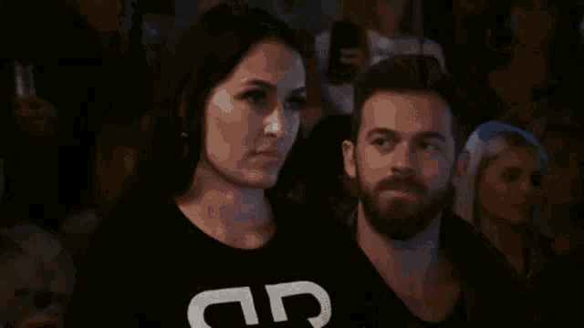 a man and a woman are sitting in a crowd of people .