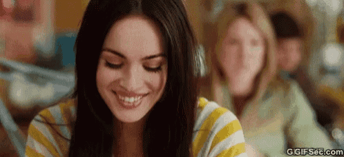 a woman in a yellow and white striped shirt is smiling and looking at the camera .