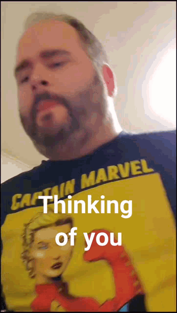 a man is wearing a captain marvel shirt