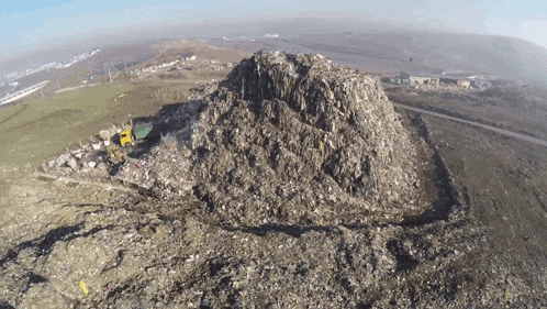 a large pile of garbage sits on top of a dirt hill