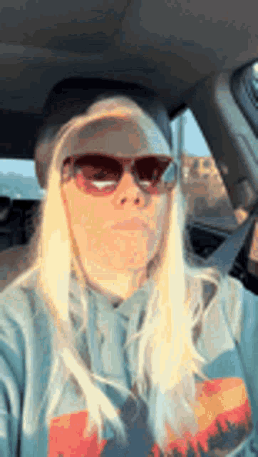 a woman wearing sunglasses and a hat is sitting in the back seat of a car .