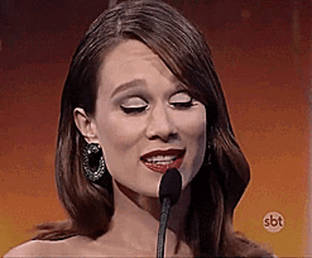 a woman singing into a microphone with sbt written on the bottom