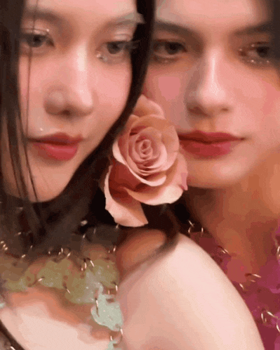 two women are posing for a picture and one has a pink rose in her hair