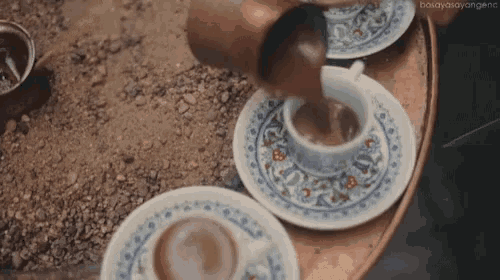 a cup of coffee is being poured into a cup on a saucer on a table .