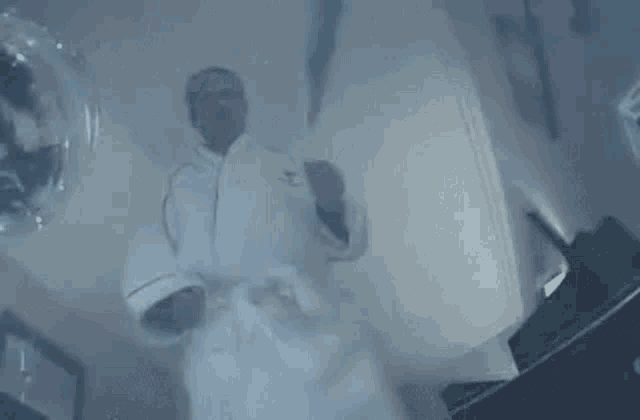 a man in a bathrobe is dancing in a room with a balloon in the background .