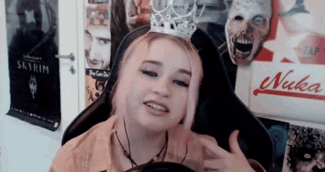 a girl wearing a crown sits in front of a poster for nuka