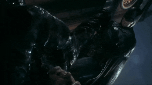 a man in a batman costume is laying down in the dark