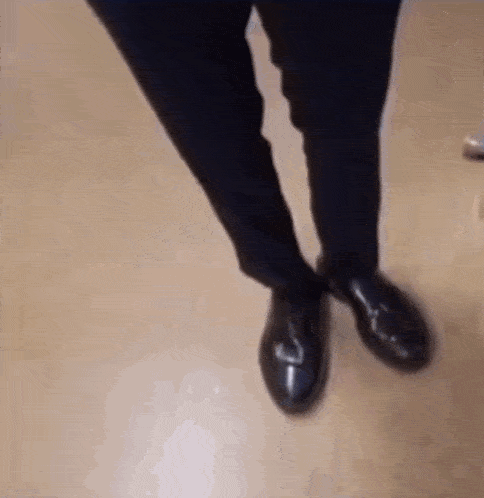 a close up of a person 's feet wearing black shoes .