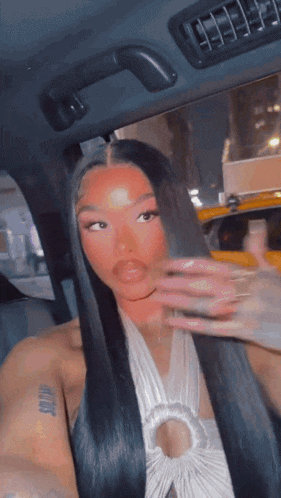 a woman with long black hair is sitting in a car