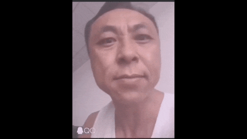 a man is making a funny face while wearing a white tank top .