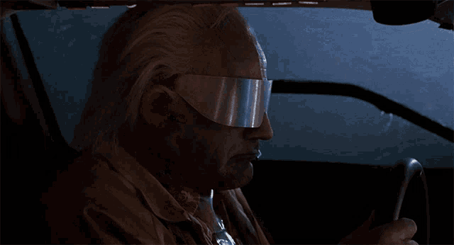 a man smoking a cigarette while driving a car at night