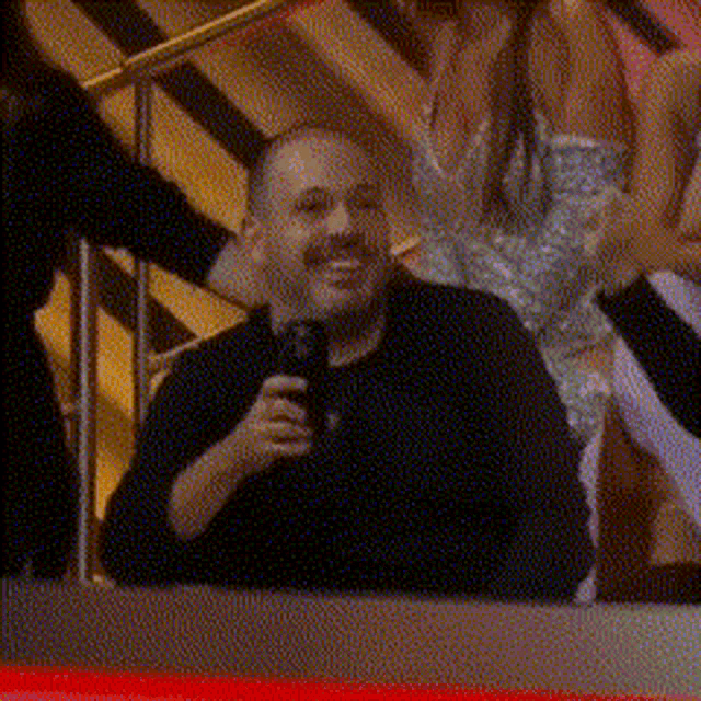 a man in a black shirt is holding a microphone in his hand