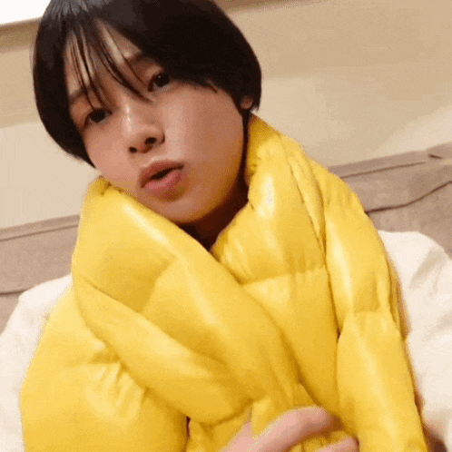 a woman wearing a yellow scarf around her neck looks at the camera
