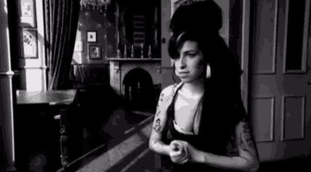 a black and white photo of a woman in a room with a fireplace