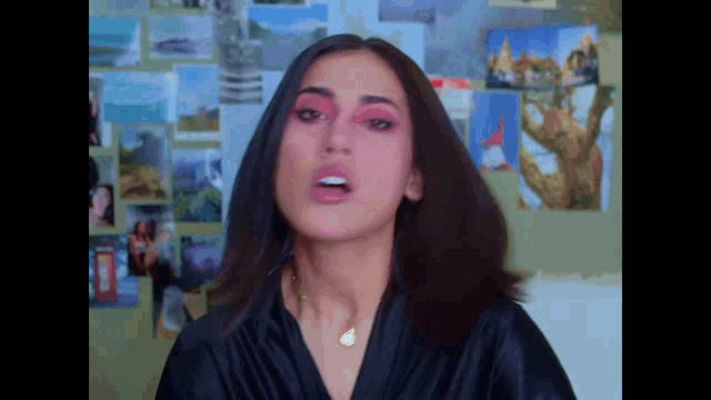 a woman in a black robe with pink eye shadow looks at the camera