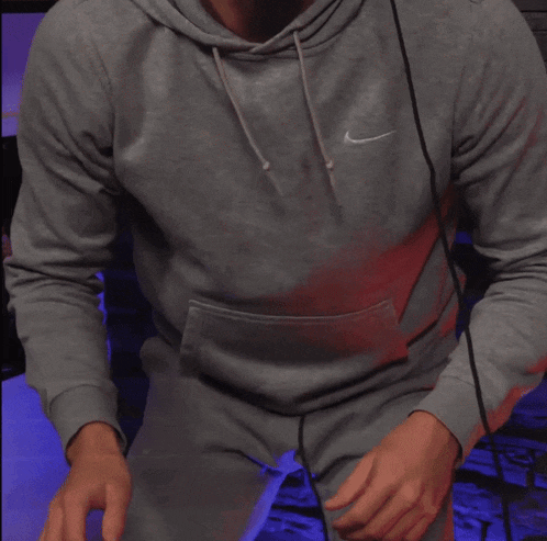 a man wearing a grey nike hoodie is sitting with his arms crossed