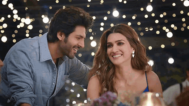 a man and a woman are smiling at each other in front of lights